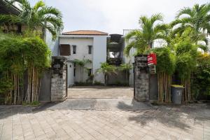 a gate to a house with palm trees in front of it at OYO 2417 Panen House in Seminyak