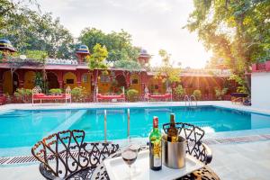 a table with wine bottles on it next to a swimming pool at Bundelkhand Riverside in Orchha