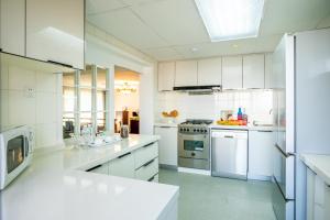 una gran cocina blanca con armarios y electrodomésticos blancos en Beijing Lido Place Apartment, en Beijing