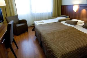 a hotel room with two beds and a chair at Spa Hotel Rauhalahti in Kuopio