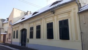 a white building with black shutters on a street at Casa Bella in Sibiu