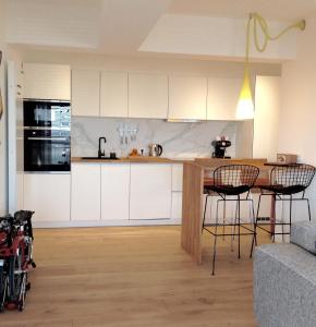 - une cuisine avec des placards blancs, une table et des chaises dans l'établissement 22ndFloor Luxury Suite, à Ostende