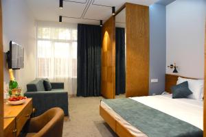 エレバンにあるR&R Hotelのベッド、椅子、テレビが備わるホテルルームです。