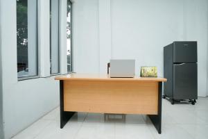 a desk with a laptop on top of it next to a refrigerator at Super OYO 2489 Choco 88 Residence in Probolinggo