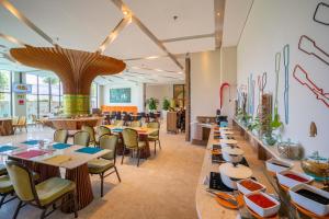 a restaurant with tables and chairs and a cafeteria at Grand Livio Kuta Hotel in Legian