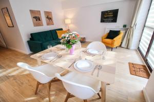 - une table à manger avec des chaises blanches et un canapé vert dans l'établissement Aparthotel City Center Apartments, à Krynica-Zdrój