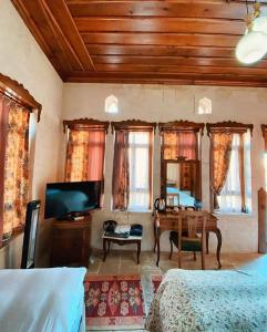 a bedroom with a bed and a desk and a tv at Elci Konagi Butik Hotel in Urfa