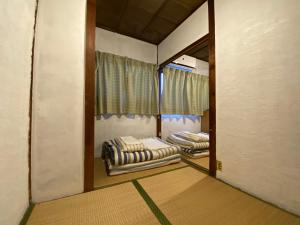a small room with two beds and a window at Yadokari House in Okayama