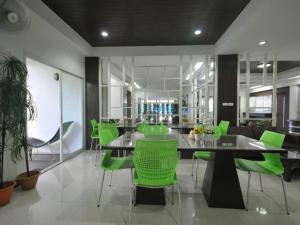 a dining room with a table and green chairs at P Park Residence Suvarnabhumi in Bangkok