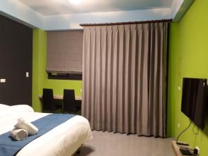 a bedroom with green walls and a bed and a television at 62 House in Hualien City