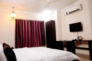 1 dormitorio con cama y cortina roja en Hotel Golden Sunrise inn en Amritsar