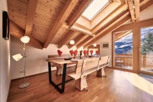a dining room with a long table and a large window at Chalet Bergfrieden Penthouse in Wengen