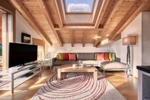 a living room with a couch and a tv at Chalet Bergfrieden Penthouse in Wengen