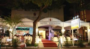 a hotel entrance with people sitting outside at night at Hotel Edelweiss in Lido di Jesolo