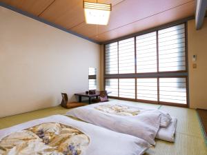 a bedroom with a bed and a window at Tabist Sakadojo Minamiuonuma in Minami Uonuma
