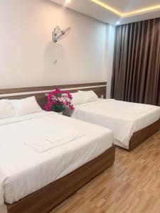 two beds in a hotel room with flowers on them at Minh Hoàng Hotel in Tuy Hoa