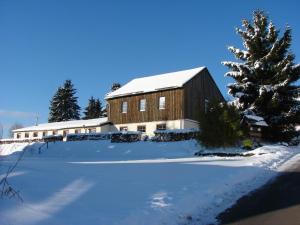 a barn with snow on the ground next to a tree at Oberes Ourtal Lodge in Bullange