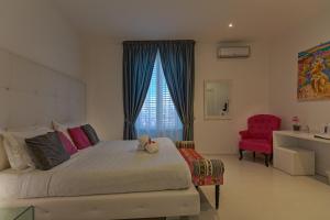 パレルモにあるパルコ ルームズ ＆ スイーツのベッドルーム1室(ベッド1台、赤い椅子付)