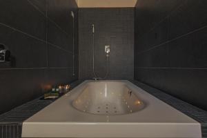 a white bath tub in a bathroom with black tiles at Palco Rooms&Suites in Palermo