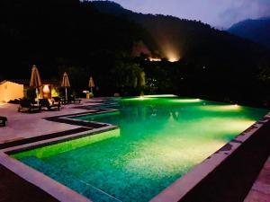 a swimming pool lit up at night at Aloha Serenity Apartments in Rishīkesh