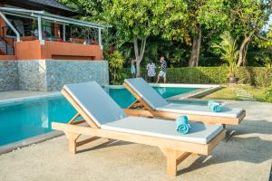 パナワビーチにあるNam Bo villa by Loftyのスイミングプールの隣に座るラウンジチェア2脚