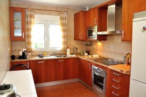 uma cozinha com armários de madeira, um lavatório e um frigorífico em Casa Bellavista Becerril em Becerril de la Sierra