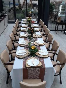 a long table with chairs and plates and flowers on it at Hotel Litovel in Komárno