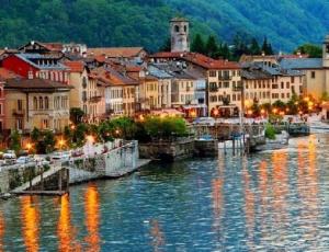 a town on a river with lights on the water at Tre ponti monolocale in Verbania