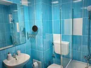 a blue tiled bathroom with a toilet and a sink at Cozy Studio in Cugir