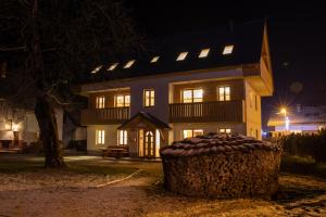 uma casa grande à noite com uma árvore em frente em Apartments & Rooms Pr' Skalovc em Bohinj