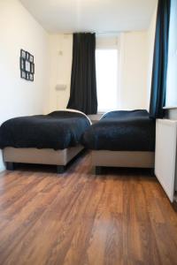 two beds in a room with a wooden floor at Appartement Lefferts in Zandvoort