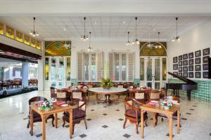 un restaurante con mesas, sillas y un piano en The Phoenix Hotel Yogyakarta - Handwritten Collection, en Yogyakarta