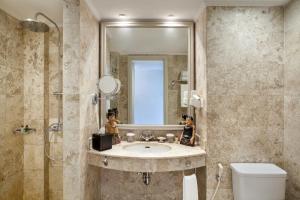 a bathroom with a sink, toilet and mirror at The Phoenix Hotel Yogyakarta - MGallery Collection - GeNose Ready, CHSE Certified in Yogyakarta