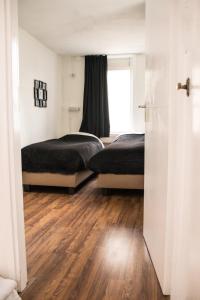 twee bedden in een kamer met houten vloeren en een raam bij Appartement Lefferts in Zandvoort