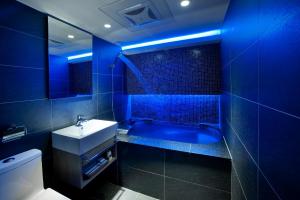 un bagno blu con lavandino e vasca di Seven Fukun Hotel a Jiaoxi