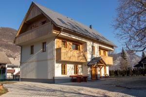 um grande edifício branco com um telhado de madeira em Apartments & Rooms Pr' Skalovc em Bohinj