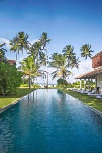 a swimming pool in a resort with palm trees at The Frangipani Tree by Edwards Collection in Unawatuna