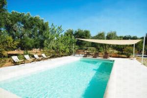 piscina con ombrellone e sedie di HelloApulia - Enchanting Trulli del Mandorlo a Ceglie Messapica
