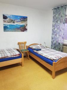 2 Betten und ein Stuhl in einem Zimmer in der Unterkunft Stabel Zimmervermietung in Lingen