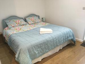a bedroom with a bed with a blue blanket and pillows at Elm Cottage Touring Park in Whitegate