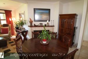 a dining room with a wooden table and chairs at Birdsong Cottage No 10 10 Poplar Drive Bergview Estate Cathkin Park in Champagne Valley +5 photos