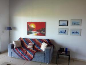 Natal Casa de Playa Coqueiros في Pitangui: غرفة معيشة مع أريكة ولوحة على الحائط