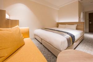 大阪市にあるIAM HOTELのベッド2台とソファが備わるホテルルームです。