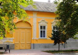 una casa amarilla con un garaje grande en Gesztenye Apartman, en Makó