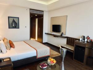 um quarto de hotel com uma cama e uma televisão em The Landmark Towers em Kanpur
