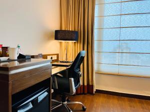 um escritório com uma cadeira, uma secretária e uma janela em The Landmark Towers em Kanpur