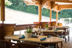 MaurouxにあるChalets du Soleilの木製のテーブルと椅子、大きな窓が備わるレストラン