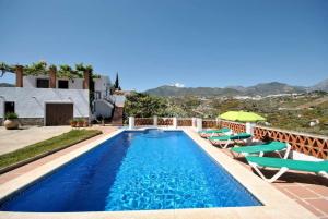 una piscina con sillas y sombrilla en Villa Ruiz, en Frigiliana