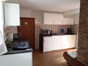 cocina con armarios blancos y encimera negra en Ferienwohnung Schäfer en Steinau an der Straße