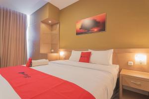 Habitación de hotel con cama grande con manta roja en RedDoorz Syariah @ Villa Grand Mutiara Tasikmalaya, en Tasikmalaya